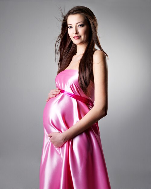 灰色のバラ色のドレスで美しい若い妊婦の肖像画