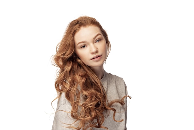 Portrait of beautiful young redhaired girl posing in casual cloth isolated over white studio background