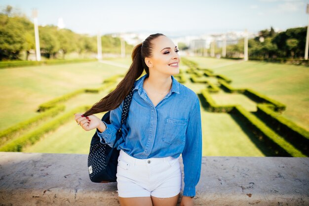 Портрет красивой молодой улыбающейся женщины в зеленом летнем городском парке
