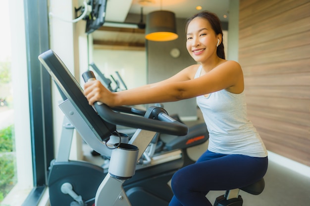 L'esercizio asiatico della donna di bello giovane sport del ritratto e risolve con le attrezzature di forma fisica in palestra