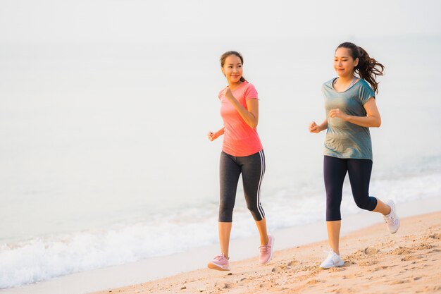 Portrait beautiful young sport asian woman running and exercise on the beach near sea and ocean at sunrise or sunset time