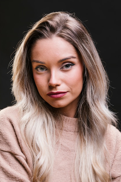 Portrait of beautiful young woman against black background looking at camera