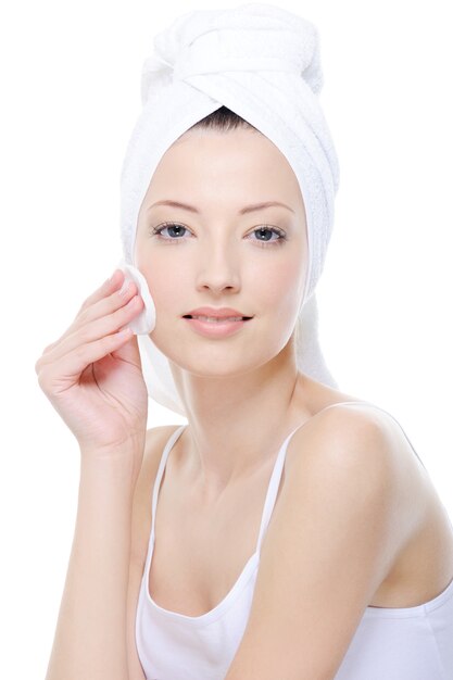 Portrait of beautiful young woman cleaning her face with cotton swab