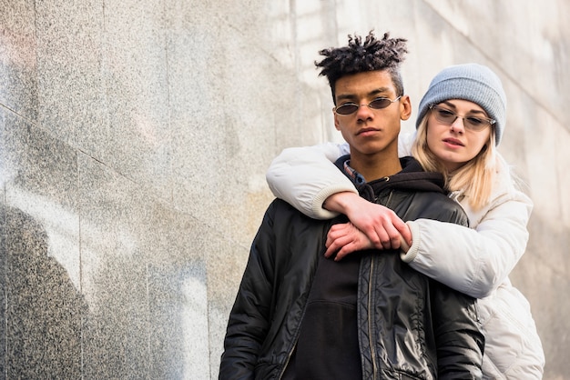 Portrait of beautiful young woman embracing her boyfriend from behind