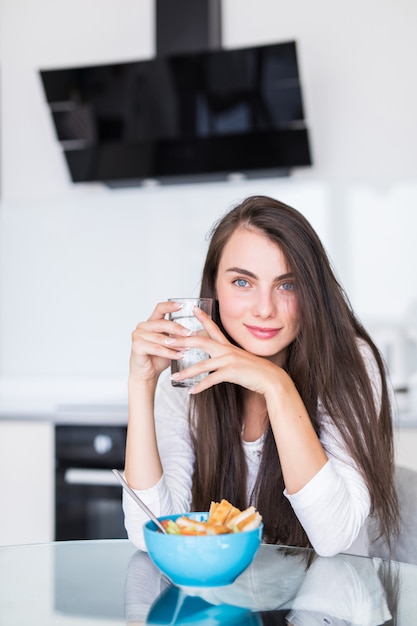 Portrait of beautiful young woman having breakfast in the kitchen.