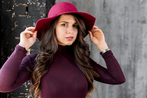 Portrait of a beautiful young woman holding hat on head with his hand