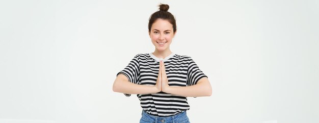 Portrait of beautiful young woman holds hands together namaste gesture say thank you expresses