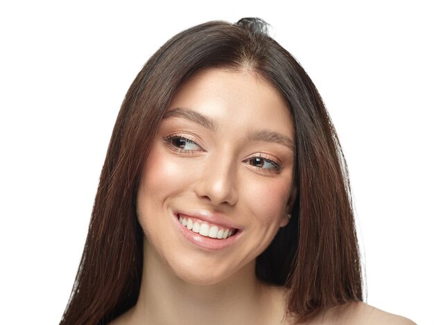 Portrait of beautiful young woman isolated on white wall. Caucasian healthy female model looking at side, smiles pretty. Concept of women's health and beauty, self-care, body, skin care.