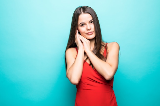 Portrait of the beautiful young woman in red dress on the blue wall