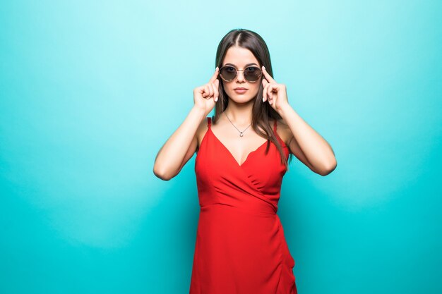 Portrait of the beautiful young woman in red dress on the blue wall