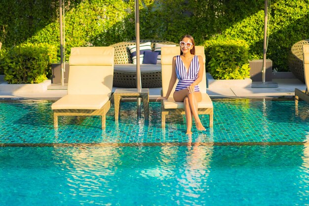 Портрет красивой молодой женщины расслабляет отдых улыбкой на отдыхе вокруг бассейна в курортном отеле