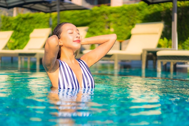 Портрет красивой молодой женщины расслабляет отдых улыбкой на отдыхе вокруг бассейна в курортном отеле