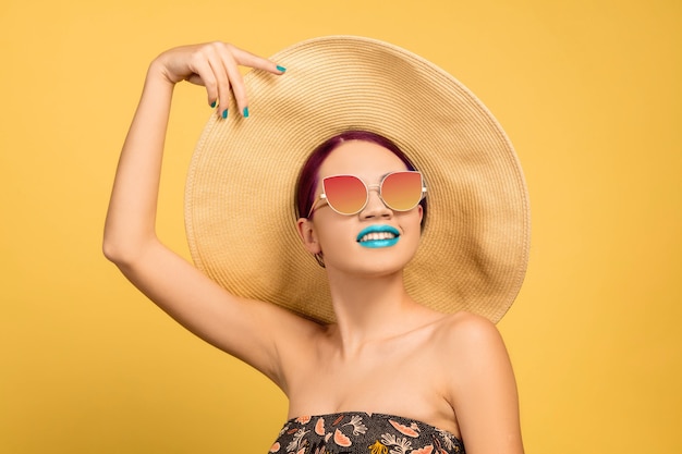 Portrait of beautiful young woman with bright make-up isolated on yellow studio wall