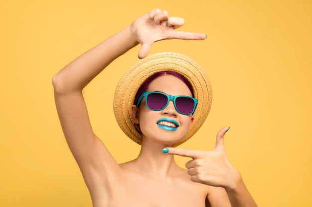 Portrait of beautiful young woman with bright make-up isolated on yellow studio