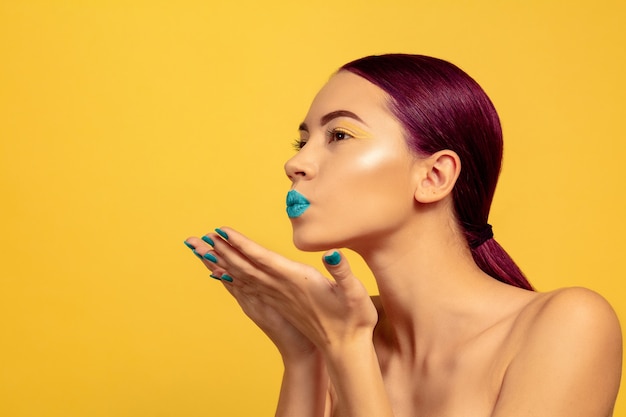 Portrait of beautiful young woman with bright make-up isolated on yellow