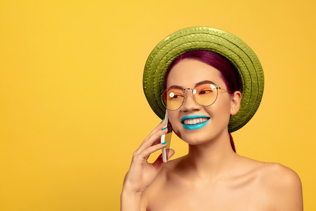 Portrait of beautiful young woman with bright make-up isolated on yellow