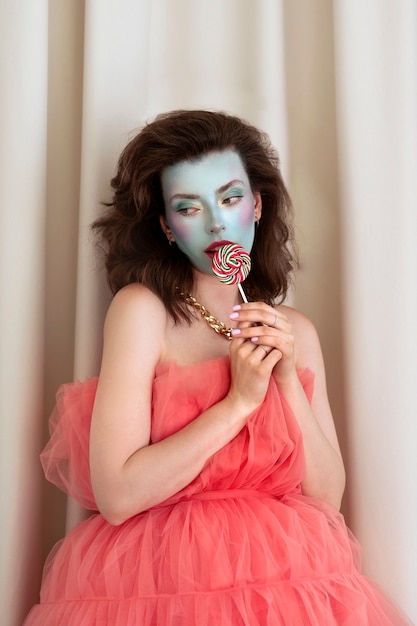 Foto gratuita ritratto di giovane e bella donna con trucco viso colorato e lecca-lecca