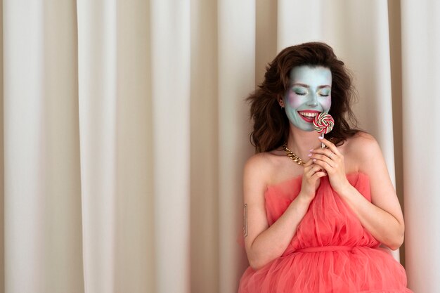 Foto gratuita ritratto di giovane e bella donna con trucco viso colorato e lecca-lecca