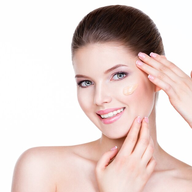 Portrait of beautiful young woman with cosmetic foundation on a skin - isolated on white background.