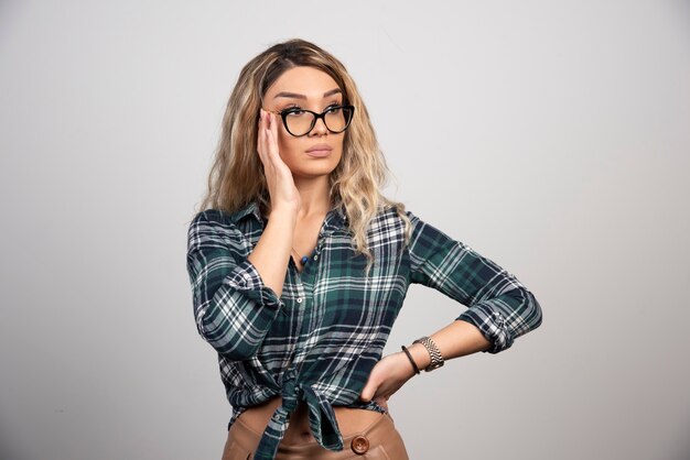 Portrait of a beautiful young woman with glasses isolated on grey background wall. 