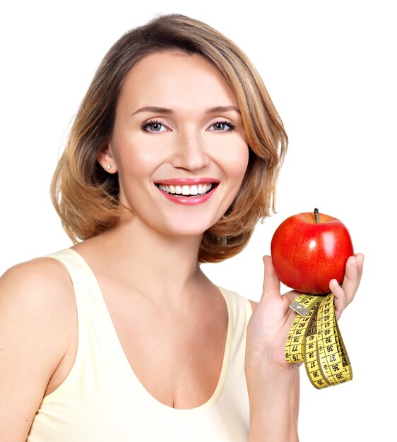 Portrait of a beautiful young woman with a measuring tape and apple isolated on white