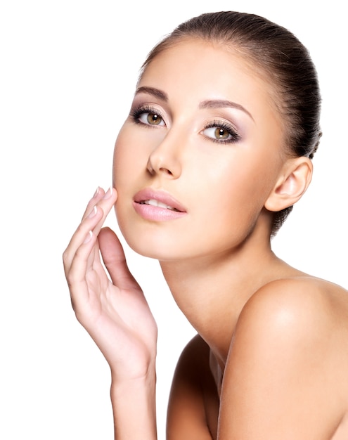 Free photo portrait of beautiful young woman with pure healthy skin gently touching her face