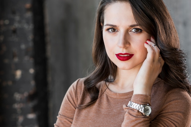 Portrait of a beautiful young woman with wristwatch on his hand looking at camera