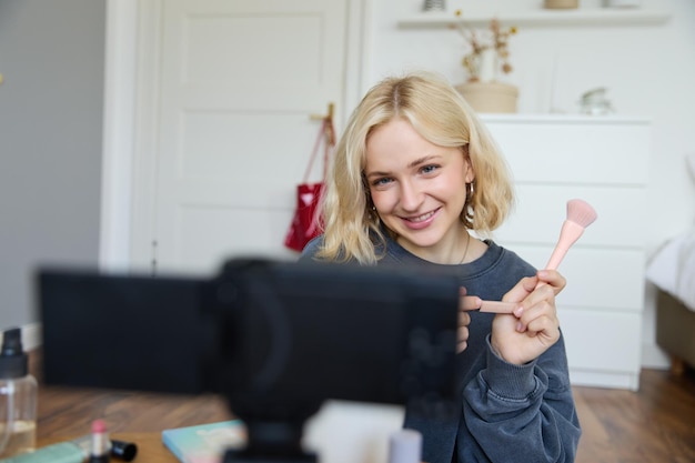 Free photo portrait of beauty blogger woman records video on camera in her room shows makeup beauty products