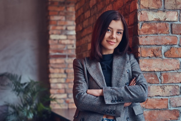 Portrait of a beauty businesswoman leaning against a brick wall