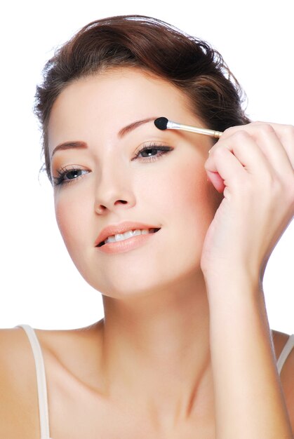 Portrait of beauty young caucasian woman applying eyeshadow using cosmetic applicator