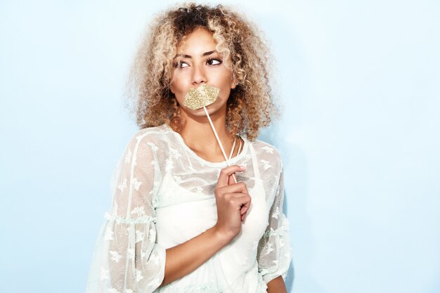 Portrait of blissful lovable woman with blond african hairstyle with big lips on stick.