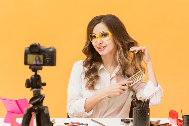 Portrait of blogger brushing hair on camera