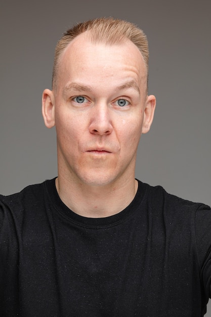 Portrait of a blond Caucasian man with blue eyes raising his eyebrow with pouting lips looking at camera. Teasing and seducing concept.