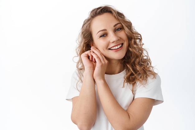 Portrait of blond lovely girl contemplating beautiful and cute scene gazing caring and heartfelt at camera standing over white background