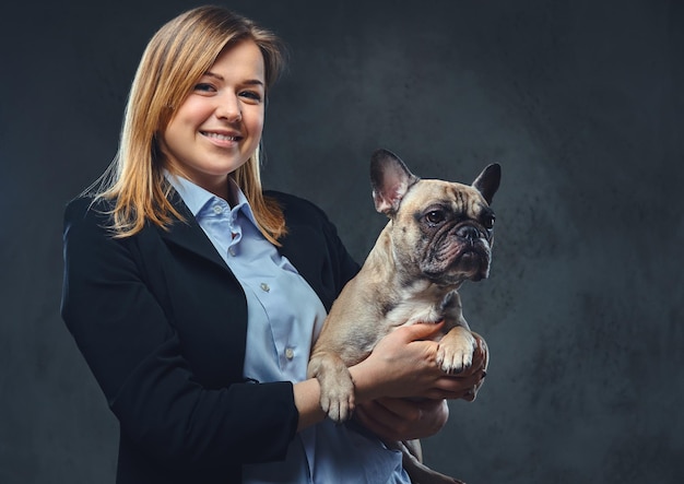 Portrait of a blonde business woman in a formal suit holds a cute dog