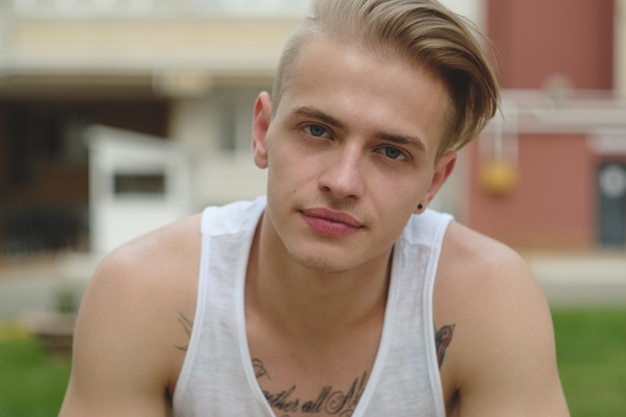 Portrait blonde hipster boy with tattoos and stylish hair