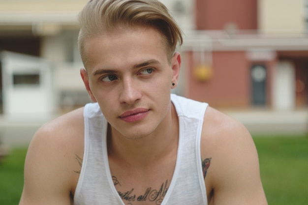 Free photo portrait blonde hipster boy with tattoos and stylish hair