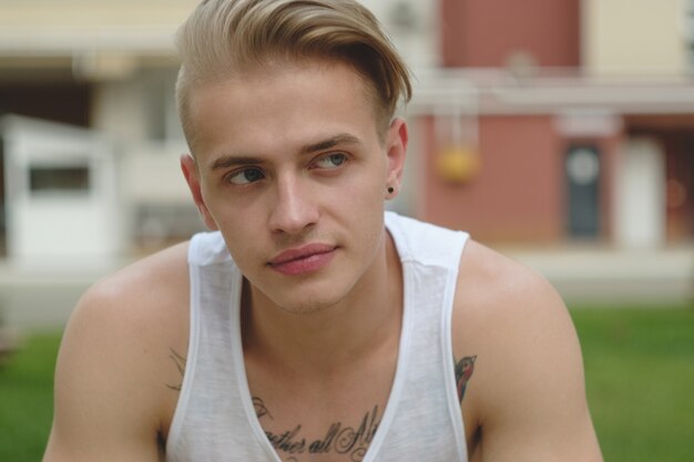 Portrait blonde hipster boy with tattoos and stylish hair