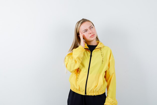 Portrait of blonde lady leaning head on hand in tracksuit and looking pensive front view