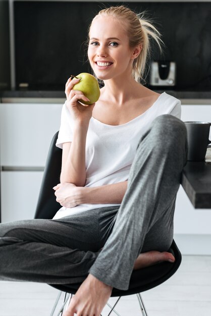 Портрет блондинка леди сидит и смотрит на кухне