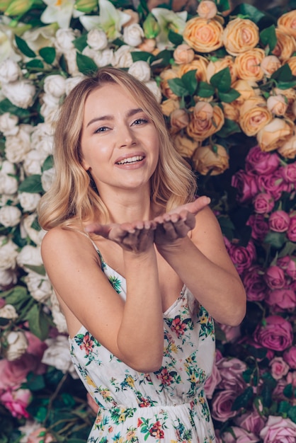 Portrait of blonde smiling young woman against roses backdrop