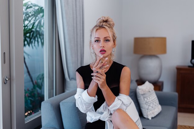 Portrait of blonde woman in body suit and white shirt with pink beautiful lips holding cigar