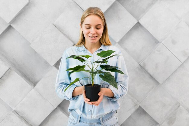 Portrait of blonde woman holding a plant