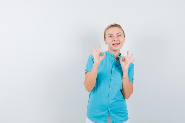 Портрет блондинки, показывающей жест в синей блузке и счастливой, вид спереди
