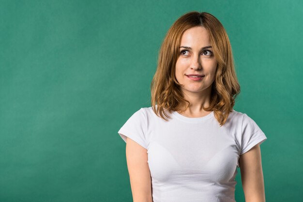 Portrait of a blonde young woman looking away against green backdrop