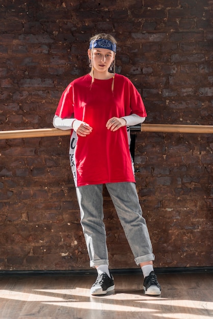 Free photo portrait of a blonde young woman standing against brick wall