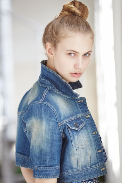 Portrait of a blue eyed blond female dressed in a denim jacket.