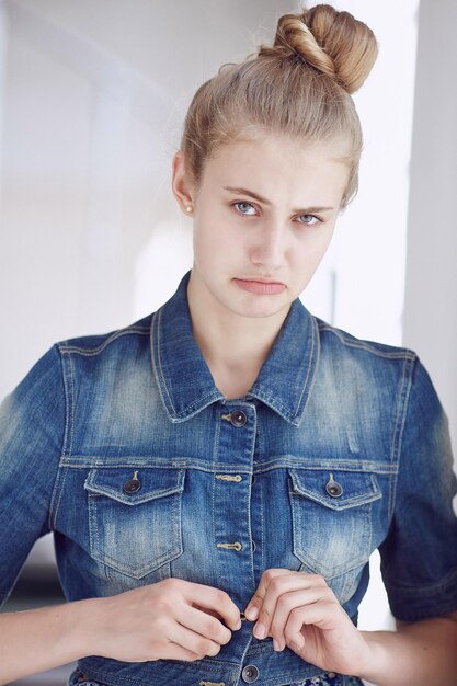 Portrait of a blue eyed blond female dressed in a denim jacket.