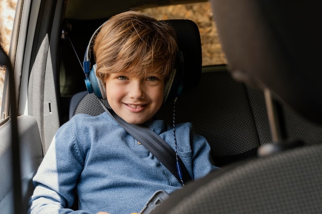 音楽を聞いているヘッドフォンと車の中で肖像画の少年