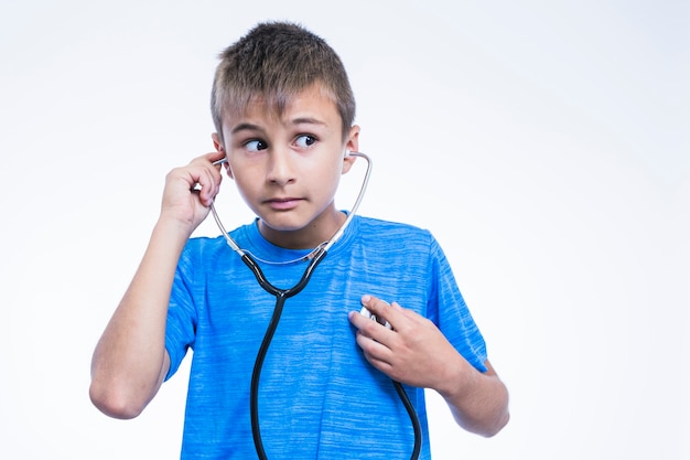 Портрет мальчика, проверка его сердцебиение с стетоскоп на белом фоне